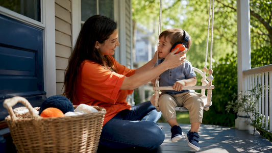 Mother adjusting earmuffs for toddler at kitchen table